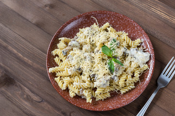 pasta with mushroom sauce, grated cheese and Basil sprig, fork on wooden background