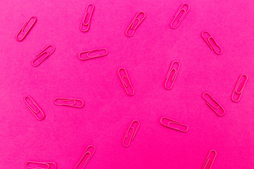 Paper clips on plastic pink background. Multicolor trendy backdrop