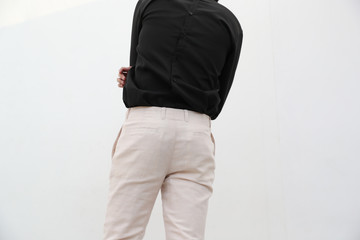 close-up of a handsome man in black V-neck shirt and white long trousers.