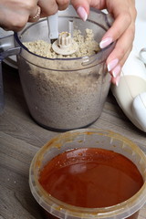Honey in a container. Near in a blender chopped peanuts and sunflower seeds. Ingredients and tools for making halva.
