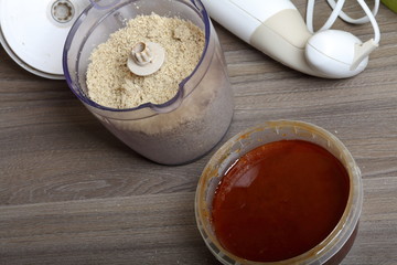 Honey in a container. Near in a blender chopped peanuts and sunflower seeds. Ingredients and tools for making halva.