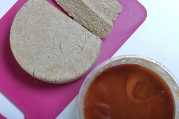 Sliced halva from honey, peanuts and sunflower seeds. Next honey in the container. Ingredients and tools for making halva.
