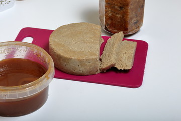 Sliced halva from honey, peanuts and sunflower seeds. Near honey in different containers. Ingredients and tools for making halva.