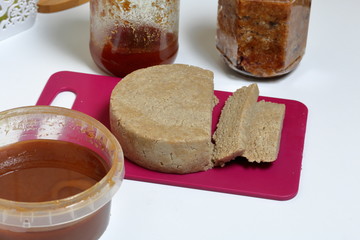 Sliced halva from honey, peanuts and sunflower seeds. Near honey in different containers. Ingredients and tools for making halva.
