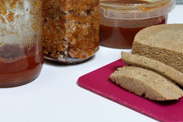 Sliced halva from honey, peanuts and sunflower seeds. Near honey in different containers. Ingredients and tools for making halva.