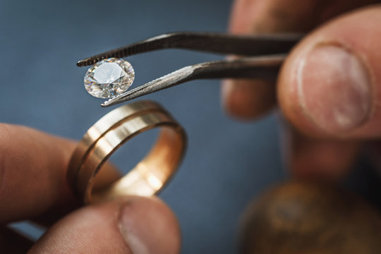 The jeweler estimates the gem to a gold blank for a future ring, close-up