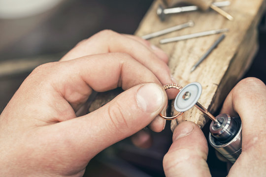 Jeweler polishes a gold ring with a special tool. Workflow in the workshop close-up.
