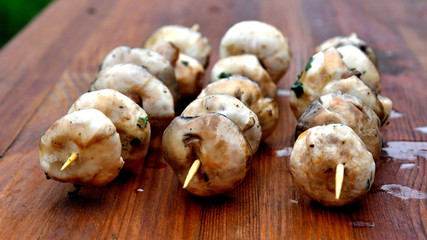 Mushrooms on a wooden skewer, picnic, wooden background.