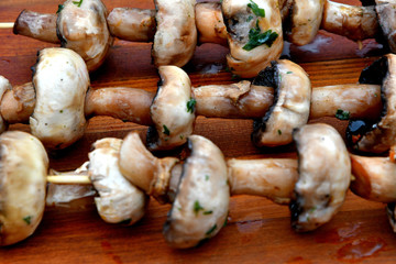 Mushrooms on a wooden skewer, picnic, wooden background.