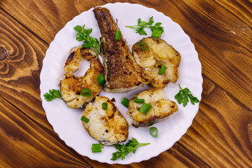 Roasted pollock in white plate on a wooden table