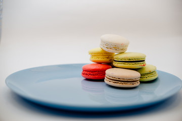 collection of colorful French  Macarons are next to each other on a blue plate on white background