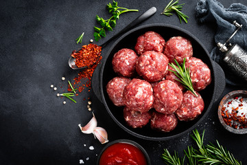 Fresh raw beef meatballs with spices and tomato sauce