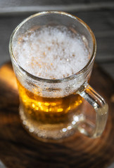 Mug of fresh light beer on wooden background