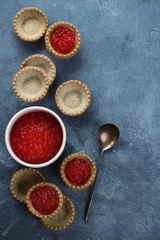 Fototapeta na wymiar Tartlets filled with red caviar, flatlay on a blue stone background, vertical shot with copy space