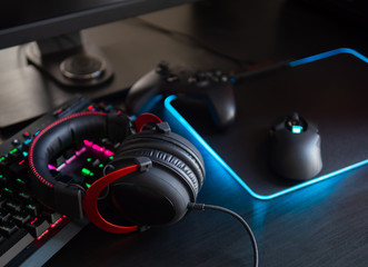 gamer work space concept, top view a gaming gear, mouse, keyboard with RGB Color, joystick, headset, webcam, Headset on black table background.