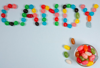 Candy writen in jelly beans at a blue background with copy space for your own text