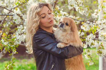 Nice woman with cute dog at garden . Pet adoption, life of pets. Female carrying a pet , animals...