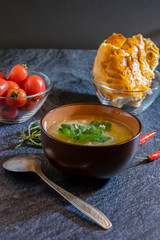 Light soup in chicken broth, with noodles and spices on a dark background. Vertical orientation
