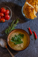 Light soup in chicken broth, with noodles and spices on a dark background. Vertical orientation