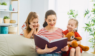 mother reading a book to daughters