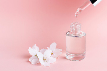 Obraz na płótnie Canvas Serum and dropper on a pink background close-up, natural cosmetics concept