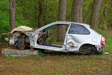 frame one gray disassembled car in the grass among the trees in the forest