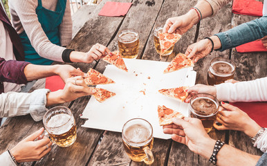 Happy friends eating take away pizza and drinking beer