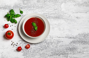 Traditional Spanish cold tomato soup gazpacho in a white bowl on a grey stone background. Traditional Spanish food. Concept of Spanish cold soup made of ripe tomatoes. Copy space, top view soup. 