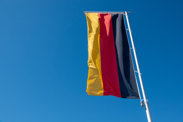 a German flag blows in front of a blue sky