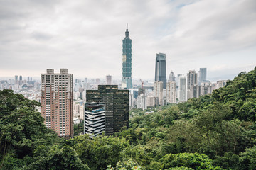 Aerial panorama over Downtown Taipei with Taipei 101 Skyscraper with trees on mountain in foreground from Xiangshan Elephant Mountain in the evening.