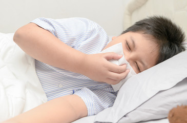 Obraz na płótnie Canvas Sick boy blowing the nose by tissue
