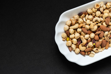 nuts, cashew nuts, dry almonds all close up on a plate, dry foods on black ground, nuts,