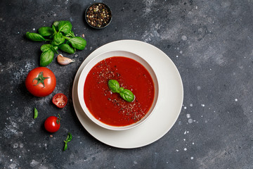 Traditional Spanish cold tomato soup gazpacho in a white bowl on a dark stone background. Traditional Spanish food. Concept of Spanish cold soup made of ripe tomatoes. Copy space, top view soup.