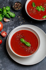 Traditional Spanish cold tomato soup gazpacho in a white bowl on a dark stone background. Traditional Spanish food. Concept of Spanish cold soup made of ripe tomatoes. Copy space, top view soup.