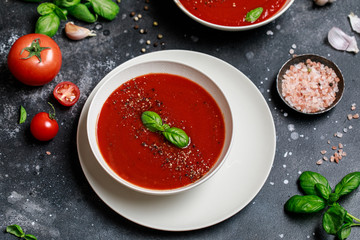 Traditional Spanish cold tomato soup gazpacho in a white bowl on a dark stone background. Traditional Spanish food. Concept of Spanish cold soup made of ripe tomatoes. Copy space, top view soup.