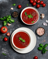 Traditional Spanish cold tomato soup gazpacho in a white bowl on a dark stone background. Traditional Spanish food. Concept of Spanish cold soup made of ripe tomatoes. Copy space, top view soup.