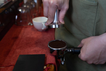 Fototapeta na wymiar Barista holds a portafilter making coffee with a coffee
