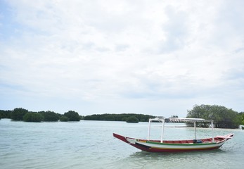 Naklejka na ściany i meble Wooden boat with fishing rod inside floating on water. A photography