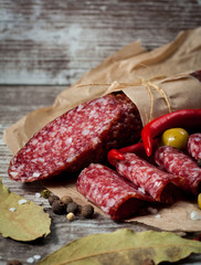 Italian salami with olives and spices on wooden background