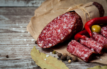 Italian salami with olives and spices on wooden background