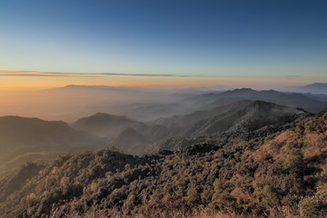 Mountain view misty morning of top hills around with the soft fog with yellow sun light in the sky background, sunrise at top of Doi Ang Khang, Chiang Mai, northern of Thailand.