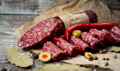 Italian salami with olives and spices on wooden background