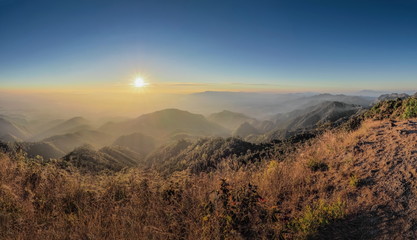 Mountain view misty morning of top hills around with the soft fog with yellow sun light in the sky background, sunrise at top of Doi Ang Khang, Chiang Mai, northern of Thailand.