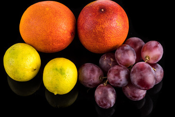 Bloody orange, lime and grapes close up close up with reflection on white and black background