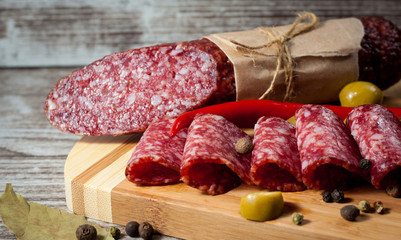 Italian salami with olives and spices on wooden background