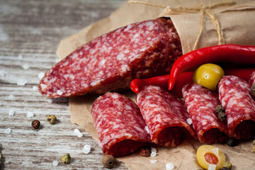 Italian salami with olives and spices on wooden background