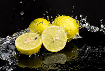 Whole lime and halves, close-up slices with water splashes