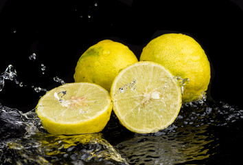 Fototapeta na wymiar Whole lime and halves, close-up slices with water splashes
