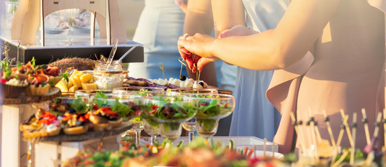 Beautifully decorated catering banquet table with different food snacks and appetizers with sandwich, caviar, fresh fruits on corporate christmas birthday party event or wedding celebration - obrazy, fototapety, plakaty
