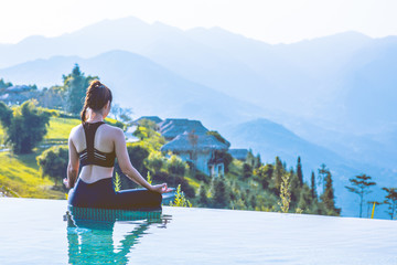 Beautiful Asian woman practice yoga Lotus pose on the pool above the Mountain peak in the morning in front of beautiful nature views in SAPA vietnam,Feel so comfortable and relax with yoga in holiday
